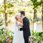 bride and groom kissing at alter with water and trees in background