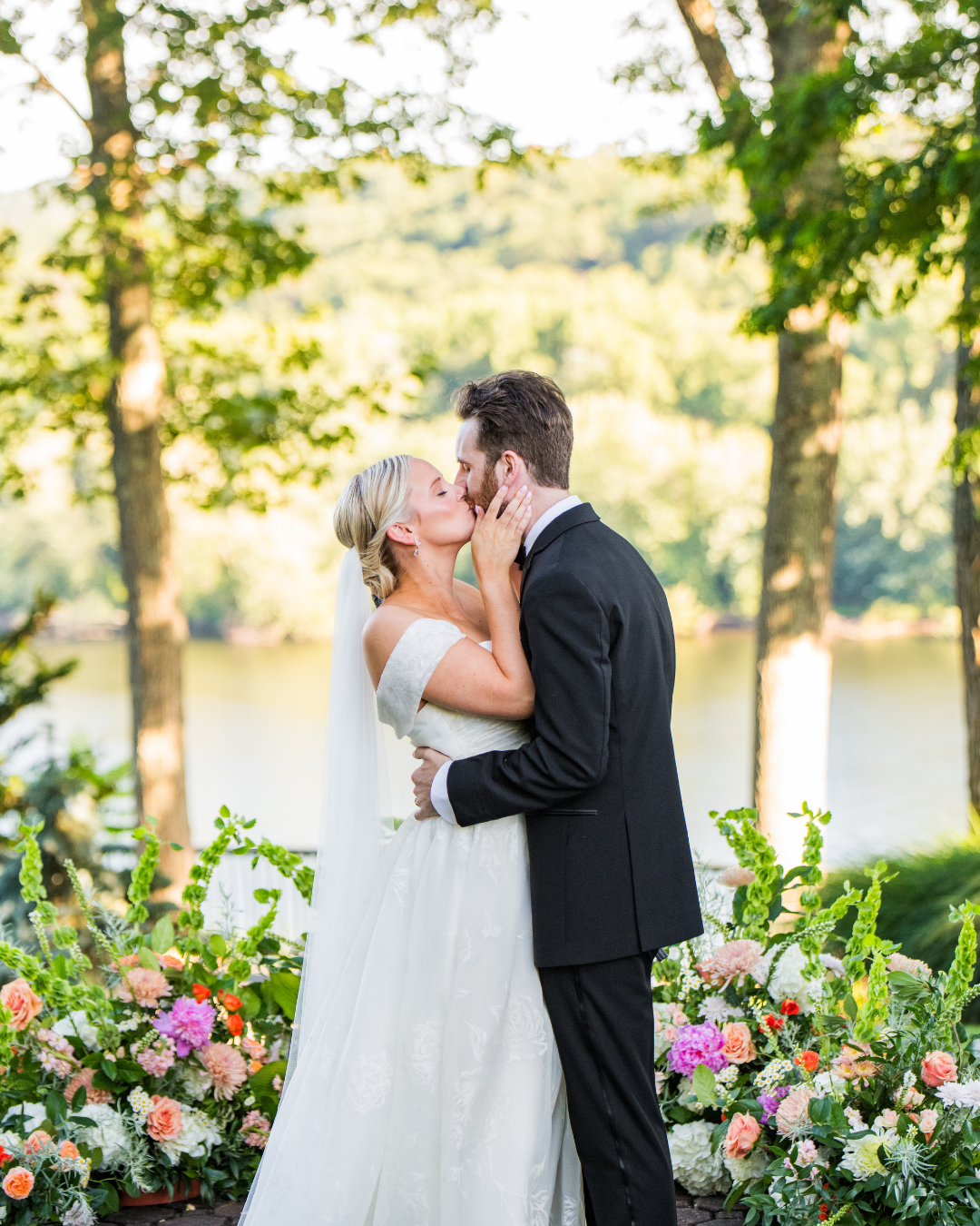 bride and groom kissing at alter with water and trees in background