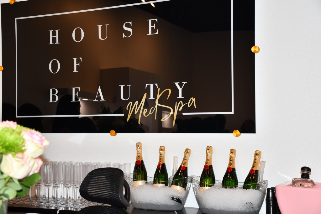 House of Beauty MedSpa reception area with champagne service and branded signage