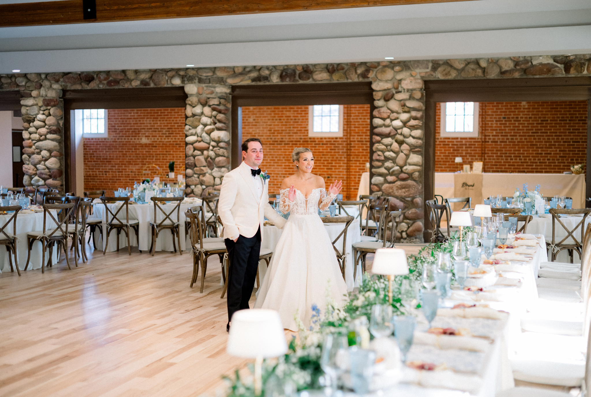 Bride and groom walk through rustic reception venue with stone archways and elegant table settings