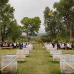 Outdoor wedding ceremony framed by vintage doors with wine barrel aisle markers and mountain backdrop