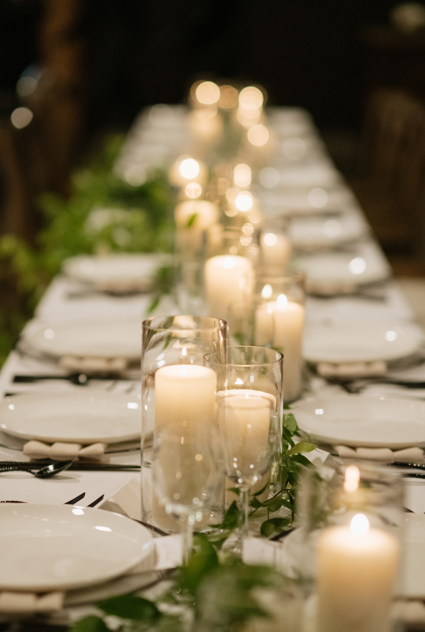 Candlelit wedding reception table with greenery garland centerpiece