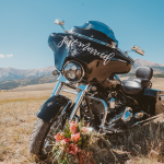 Motorcycle with "just married" sign and floral bouquet in Colorado mountain landscape