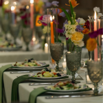 Elegant wedding tablescape with colorful floral centerpieces, candles, and green table runner