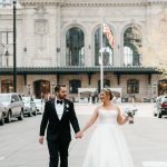 Bride and groom holding hands outside Denver Union Station on their wedding day