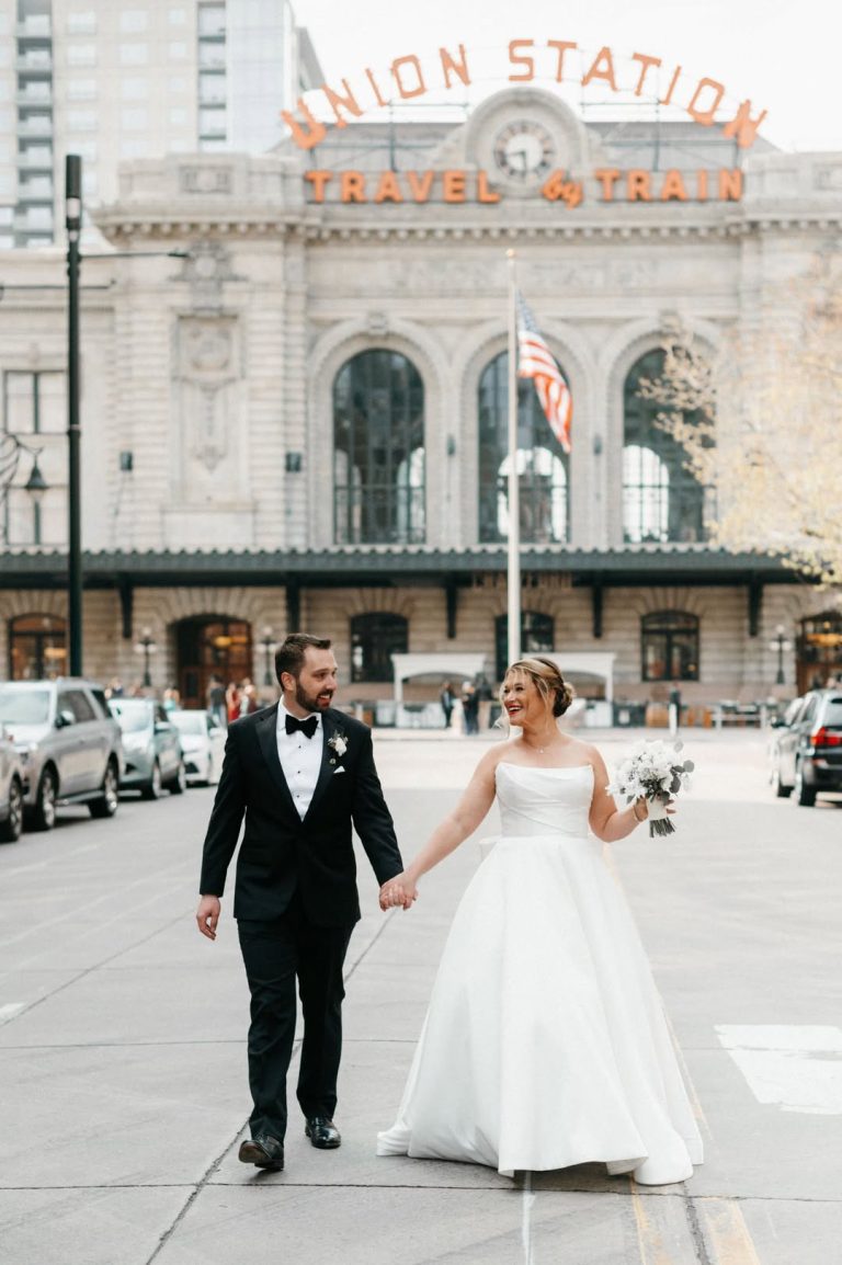 Bride and groom holding hands outside Denver Union Station on their wedding day