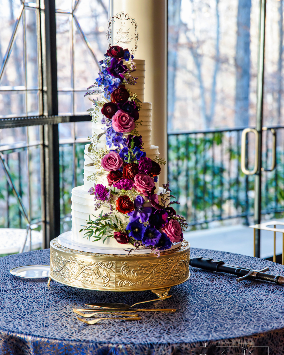 three tiered wedding cake with bold and colorful florals, in dark blue, pink and purple