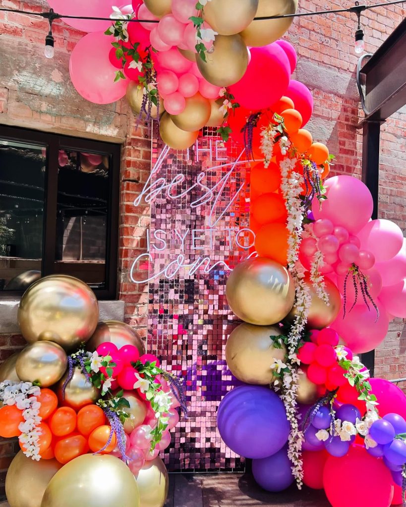 Festive balloon arrangement with oversized round balloons in vibrant colors and botanical elements for special event