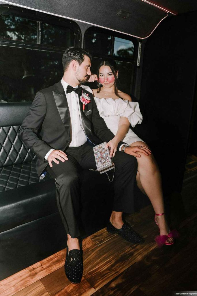 Newlywed couple sitting in luxury party bus with quilted leather seating and string lights