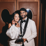 Bride and groom posing with vintage rotary telephone against art deco wood paneling