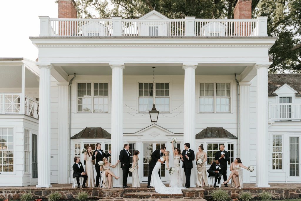 Bridal party mingling on white columned porch of classic Southern estate venue