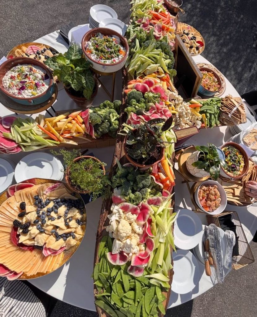 Colorful grazing table spread with vegetables, dips, cheese, and charcuterie boards