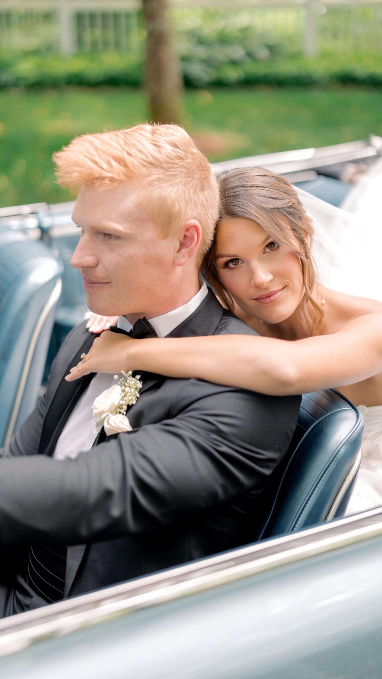 Bride and groom embracing in classic convertible car after Charlotte wedding ceremony