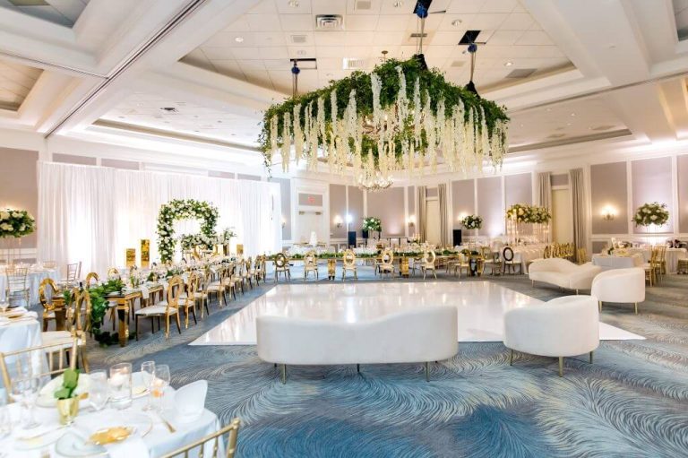 Elegant Charlotte ballroom with hanging floral chandelier, white modern lounge seating, and formal dining tables with gold accents