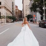 Bride in ballgown wedding dress with dramatic train walking down downtown Cleveland street
