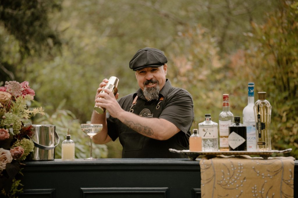 Bartender shaking cocktails at elegantly decorated outdoor bar setup at Colorado wedding