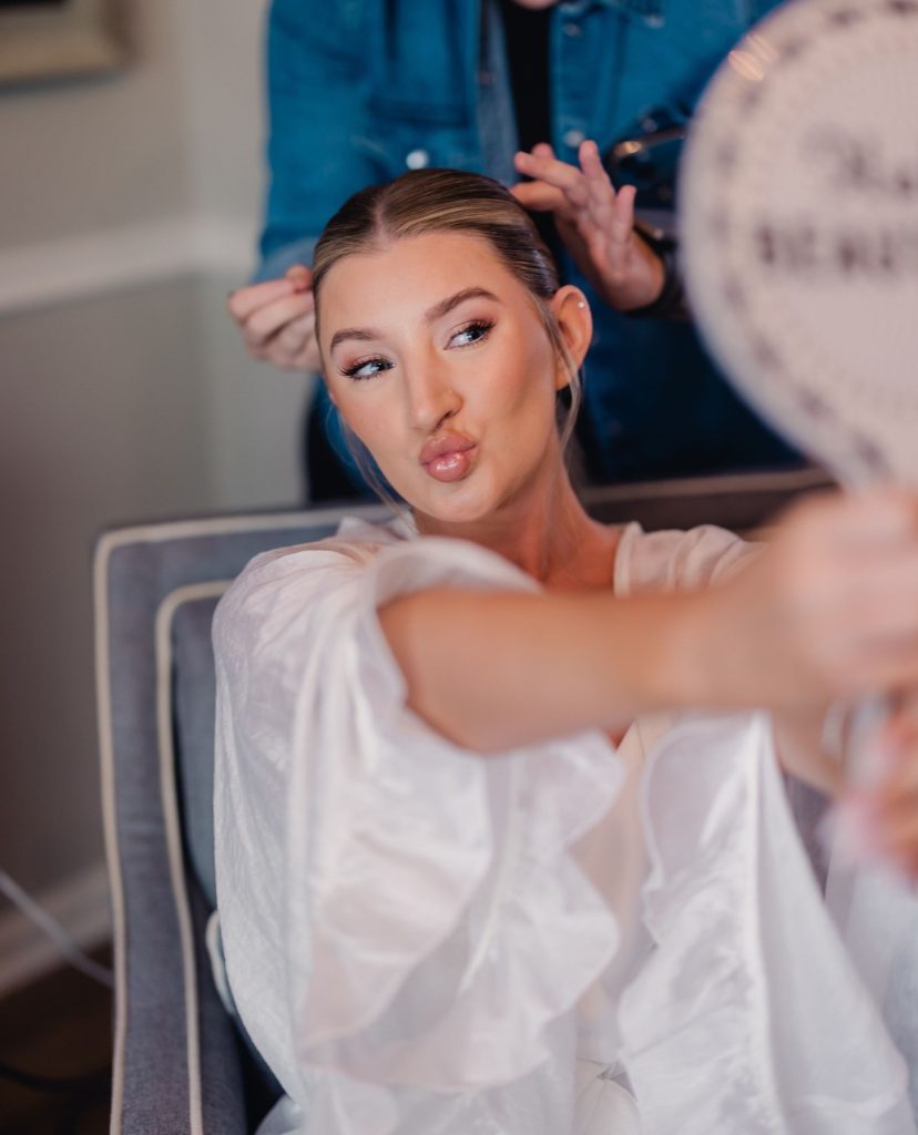 Bride getting hair styled by professional stylist while looking in mirror