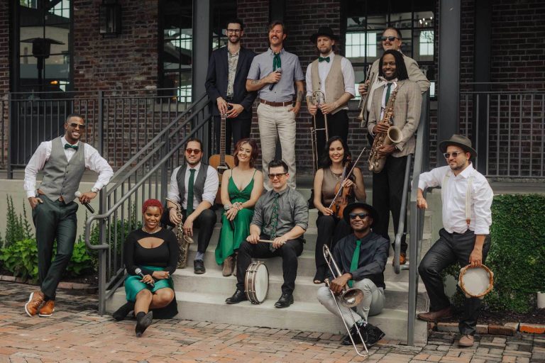 Charlotte wedding band posing with instruments including saxophone, violin, guitar, trombone, and drums on brick patio