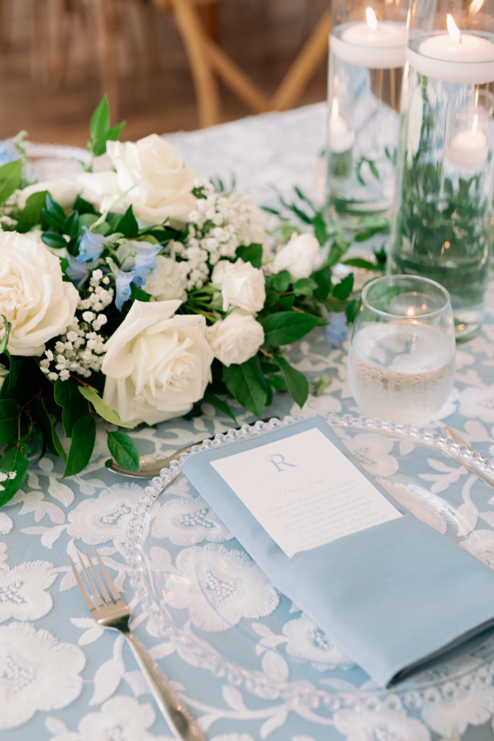 a blue and white tablescape for a wedding reception with sky blu linen napkin and stemless wine glass