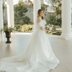 Bride twirling in flowing white gown on sunlit porch of Southern venue