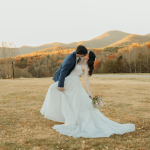 Newlyweds kissing in mountain field during golden hour with fall foliage