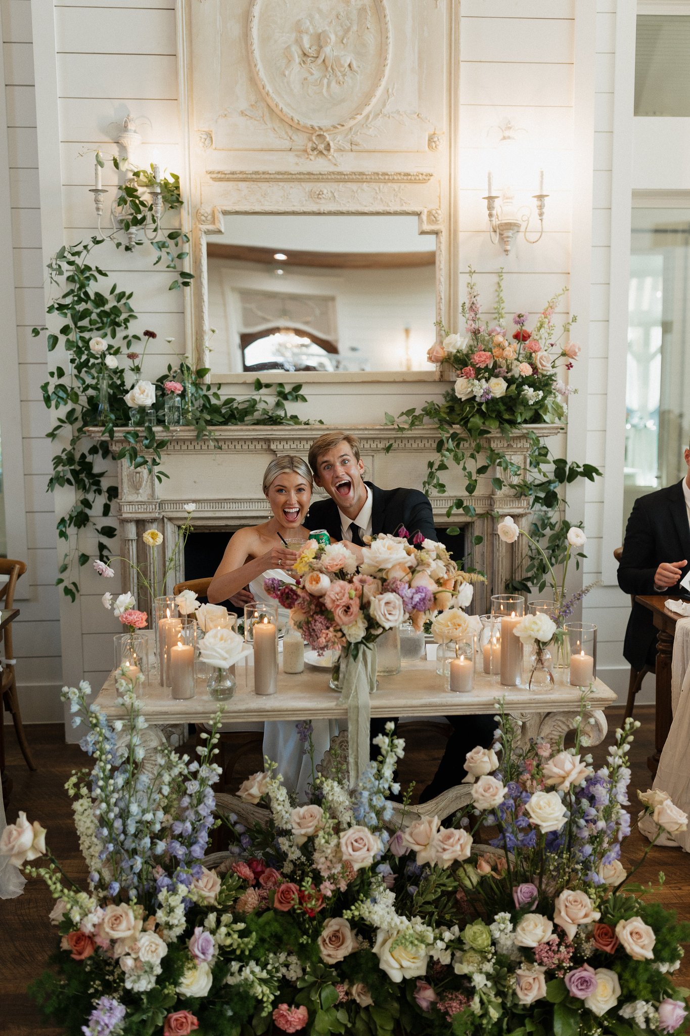 couple seated at head table surrounded by stunning florals at wedding reception