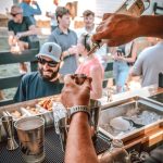 Professional bartender pouring craft cocktail into copper cup at elegant Denver event venue