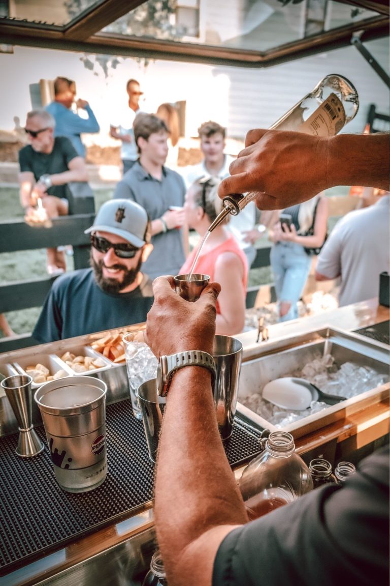Professional bartender pouring craft cocktail into copper cup at elegant Denver event venue
