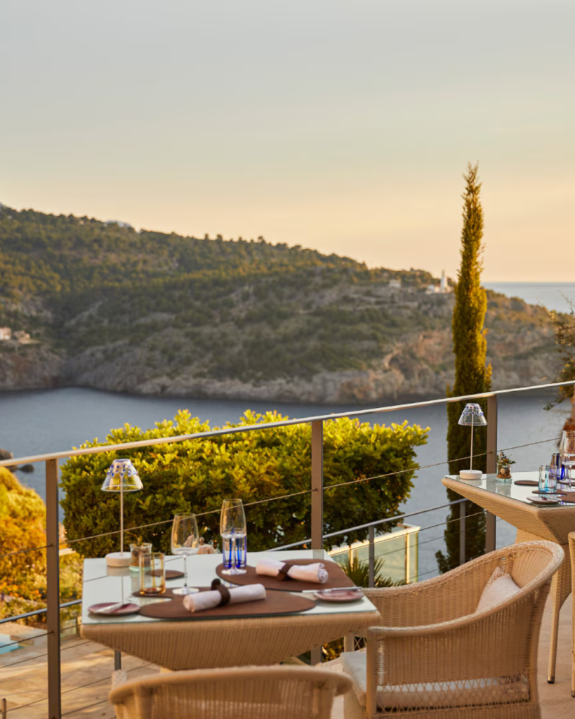 Outdoor reception setup with waterfront and hillside views at sunset