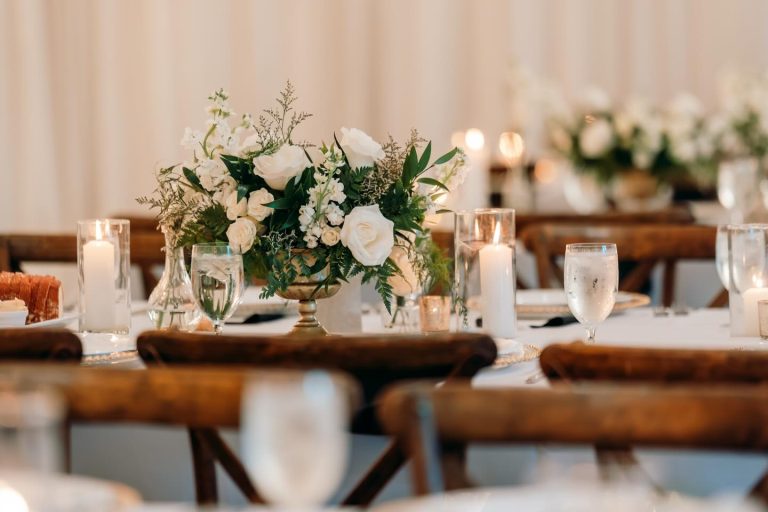Rustic wooden farm tables with lush floral centerpieces and elegant place settings at barn wedding reception