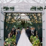 Beautiful greenhouse setting at Jorgensen Farms featuring lush greenery, drapery and glass ceiling.