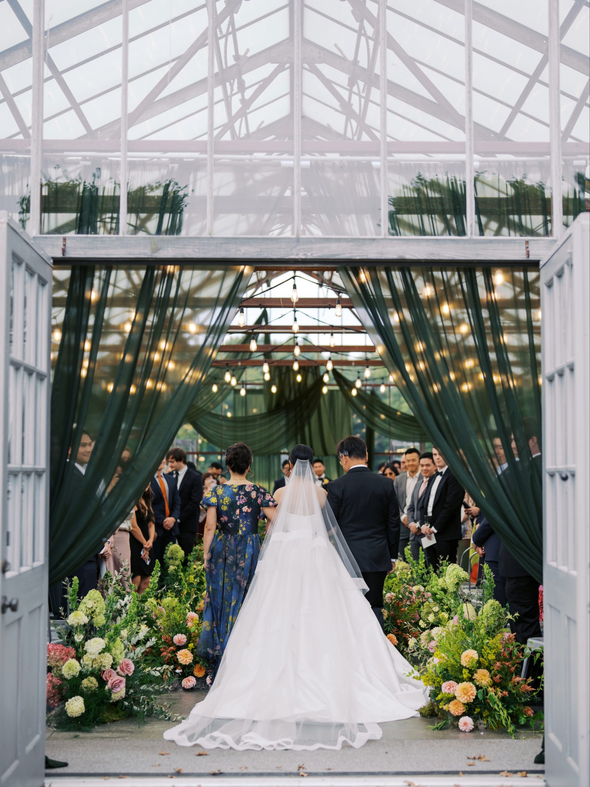 Beautiful greenhouse setting at Jorgensen Farms featuring lush greenery, drapery and glass ceiling.