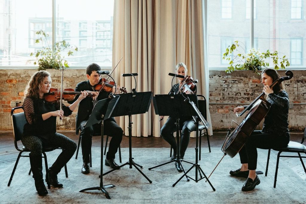 String quartet performing in elegant industrial loft venue with exposed brick and large windows