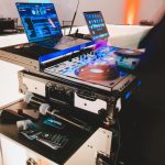 Professional DJ equipment setup with turntables, laptop, mixer, and wireless microphones on flight case