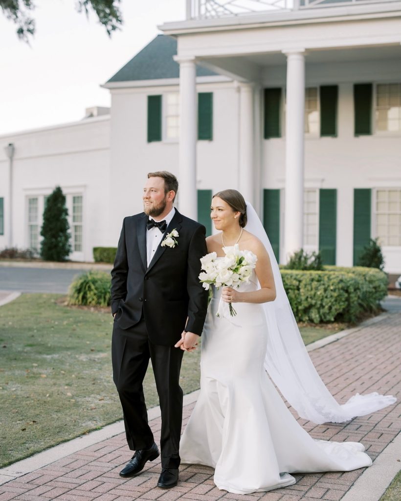 Bride and groom walking hand in hand outside a white-columned Columbus wedding venue.