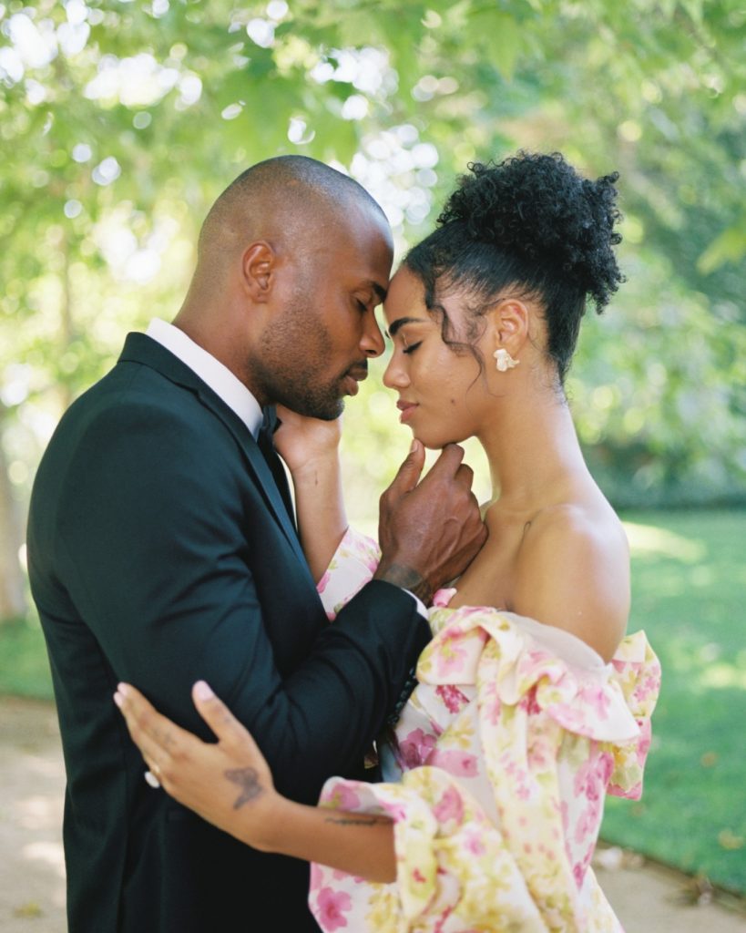 Intimate moment between couple in formal attire embracing outdoors with soft natural lighting