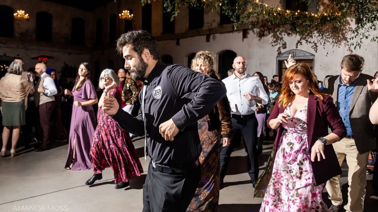 Wedding guests dancing energetically at an elegant Charlotte reception venue with chandelier lighting