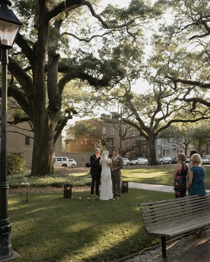 Outdoor wedding ceremony under majestic oak trees in a Savannah park with officiant and couple exchanging vows