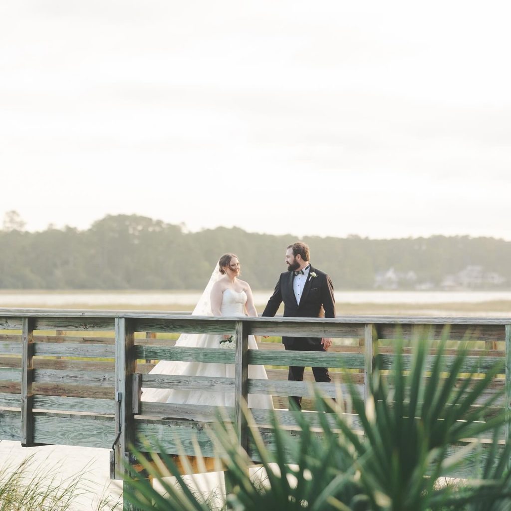 Bride and groom standing together on waterfront deck overlooking coastal Georgia marshland