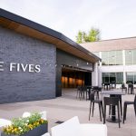 Modern outdoor patio at The Fives event venue with contemporary seating and glass-walled building