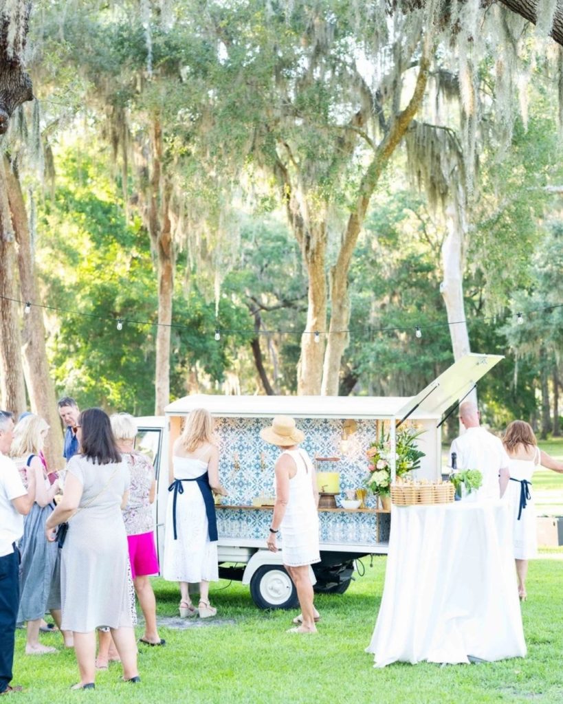 Vintage mobile bar cart set up outdoors at wedding reception under moss-draped trees