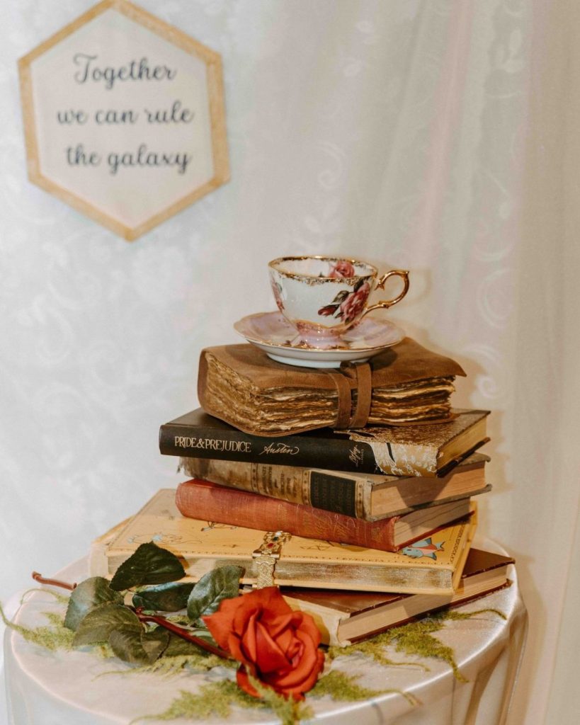 Rustic stacked book wedding cake topped with teacup and red rose