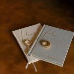 Wedding rings displayed on "Hers" and "His" vow books with gold embossing