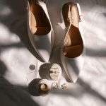 Ivory bridal heels with slingback straps displayed alongside wedding rings, earrings, and jewelry boxes in natural sunlight