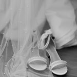 Bride's hands holding white strappy wedding heels with tulle veil in black and white