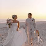 Newlyweds walking hand-in-hand on beach at sunset in coastal Georgia