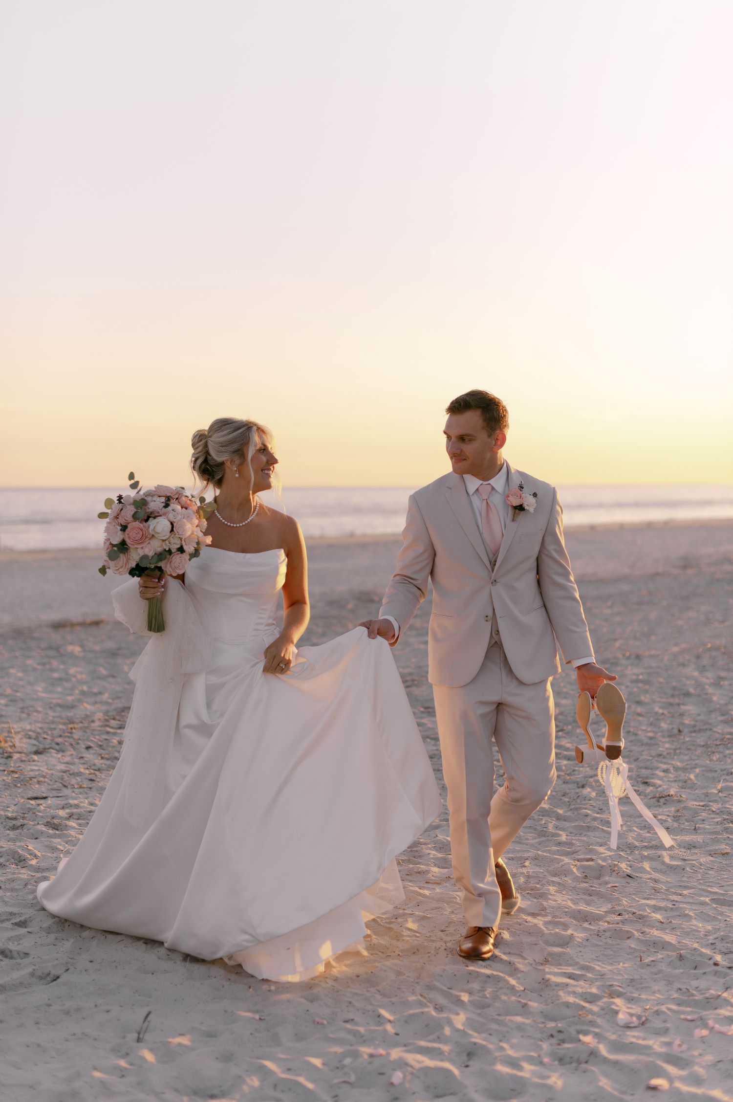 Newlyweds walking hand-in-hand on beach at sunset in coastal Georgia