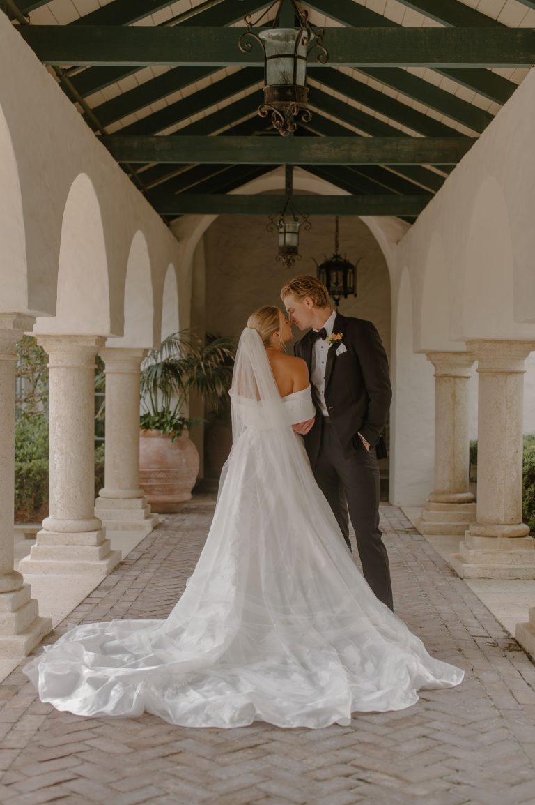 Bride and groom embracing under white columned archway at Savannah wedding venue