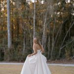 Bride in strapless ballgown twirling outdoors against autumn trees in coastal Georgia