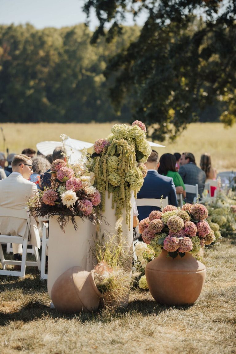 Outdoor Columbus wedding ceremony featuring organic hydrangea arrangements in pink, green and cream displayed in terracotta vessels.
